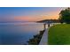 Expansive waterfront lawn with private dock on clear calm water at sunset at 218 Colony Point S Rd, St Petersburg, FL 33705