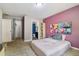 Bedroom featuring an en suite bathroom, closet, pink walls, a window, shelving, and carpeted floors at 27050 Anthony Ave, Brooksville, FL 34602