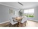 Dining room with sleek, modern chandelier, light gray walls, wood floors and a sunlit window at 2773 Seabreeze S Dr, Gulfport, FL 33707