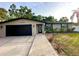 Charming single-story home with a black garage door, a landscaped yard, and a brick walkway at 3143 Phoenix Ave, Oldsmar, FL 34677