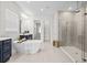 Luxurious bathroom featuring a freestanding tub, glass-enclosed shower, and stylish blue vanity at 33750 Ocean Spray Ln, Wesley Chapel, FL 33543
