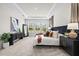 Bright Main bedroom with neutral carpet, large windows, and sleek dark-wood nightstands with decorative lamps at 33750 Ocean Spray Ln, Wesley Chapel, FL 33543