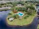 Aerial view of a community pool nestled on an island amidst a tranquil lake and lush landscaping at 3923 Shoreside Cir, Tampa, FL 33624