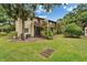 View of a patio with green grass, lush trees, and an upstairs balcony at 4215 E Bay Dr # 1005D, Clearwater, FL 33764