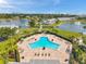 Aerial view of a large, geometric pool with lounge chairs, lush landscaping, and nearby lake views at 5260 Coquina Key Se Dr # C, St Petersburg, FL 33705