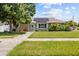 Inviting single-story home with solar panels, a well-manicured lawn, and a charming turquoise front door at 5401 3Rd N Ave, St Petersburg, FL 33710