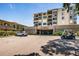 Exterior view of the condo complex with a paved parking area and a glimpse of the car entrance and a car and golf cart at 6158 Palma Del Mar S Blvd # 306, St Petersburg, FL 33715