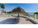 A picturesque patio scene featuring a tiki hut, table, chairs, and a serene view of the water at 6158 Palma Del Mar S Blvd # 306, St Petersburg, FL 33715