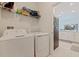 Laundry room with modern appliances, functional shelving, and tile flooring at 6542 95Th N Pl, Pinellas Park, FL 33782