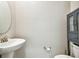 Contemporary half bathroom with a pedestal sink, round mirror, toilet, cabinet and sleek fixtures, providing convenience for guests at 6745 Citrus Creek Ln, Tampa, FL 33625