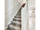 Well-lit carpeted staircase features a white handrail, modern design, and leads to upper levels of the home at 6745 Citrus Creek Ln, Tampa, FL 33625