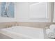 Close-up of a soaking tub surrounded by white tile and marble, with a window above at 7060 S Shore S Dr, South Pasadena, FL 33707