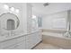 Bright bathroom with double sinks, modern lighting fixtures, a vanity and a soaking tub at 7060 S Shore S Dr, South Pasadena, FL 33707