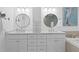 Bathroom featuring double sinks, a center storage cabinet and a separate soaking tub in the corner at 7060 S Shore S Dr, South Pasadena, FL 33707
