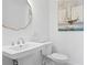 Elegant powder room features a pedestal sink, unique gold-framed mirror, and nautical-themed decor at 7060 S Shore S Dr, South Pasadena, FL 33707