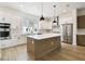 Modern kitchen boasts white cabinetry, stainless steel appliances, and a center island with pendant lighting at 7240 Sutton Ln, Sarasota, FL 34240