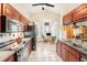 A kitchen with wood cabinets, granite countertops, black appliances, and a view of a dining area at 8135 Golf Club Ct, Hudson, FL 34667