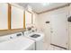 A laundry room with white appliances, white cabinets with wooden trim, and tile flooring at 8135 Golf Club Ct, Hudson, FL 34667