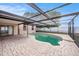 A kidney-shaped pool with a screened enclosure and brick-paved patio extends from the home at 8744 Andros Ln, Port Richey, FL 34668