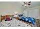 Bright bedroom features two beds with colorful linens, wood floors, and a ceiling fan at 9520 Trumpet Vine Loop, Trinity, FL 34655