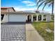 Charming single-Gathering home featuring a two-car garage, decorative archways, and mature palm trees at 9907 Island Harbor Dr, Port Richey, FL 34668