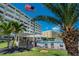 Exterior view of a condo complex featuring a pool, palm trees, and an American flag, emphasizing amenities and location at 100 Bluff View Dr # 405A, Belleair Bluffs, FL 33770