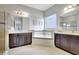 Elegant bathroom with dual vanities, a soaking tub, and a large window providing natural light at 10415 Cardera Dr, Riverview, FL 33578