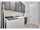 Functional laundry room with modern washer and dryer, dark cabinets, and a sink at 10415 Cardera Dr, Riverview, FL 33578