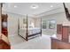 Spacious bedroom with a four-poster bed, neutral color scheme, tray ceiling, and ample natural light at 10415 Cardera Dr, Riverview, FL 33578