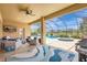 Inviting covered patio with lounge furniture, ceiling fan, and views of the pool and backyard at 10415 Cardera Dr, Riverview, FL 33578