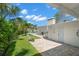 Landscaped backyard featuring a paved patio, lush greenery, and a glimpse of the pool and canal at 106 Midway Is, Clearwater Beach, FL 33767