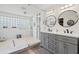 Bright bathroom with double sink vanity, glass block window, and tiled shower at 106 Midway Is, Clearwater Beach, FL 33767