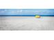 Expansive white sandy beach with a solitary yellow cabana, meeting the tranquil ocean under a clear blue sky at 106 Midway Is, Clearwater Beach, FL 33767