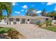 Charming single-story home with a well-manicured lawn, brick driveway, and lush landscaping, creating inviting curb appeal at 106 Midway Is, Clearwater Beach, FL 33767