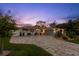 Inviting single-Gathering home featuring a paver driveway, lush landscaping, and a well-kept facade at twilight at 106 Midway Is, Clearwater Beach, FL 33767