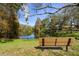 Relax by the serene pond with a peaceful bench, surrounded by lush greenery and mature trees at 1126 Tarridon Ct, Dunedin, FL 34698