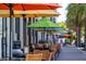 Outdoor seating at a cafe with colorful umbrellas over dark tables on the brick sidewalk at 1126 Tarridon Ct, Dunedin, FL 34698