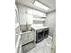 Modern laundry room with white cabinets, marble countertops, sink, and gray tile floor at 1147 Halapa Way, Trinity, FL 34655
