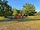 Community playground with colorful equipment and a fenced area, surrounded by mature trees at 1147 Halapa Way, Trinity, FL 34655