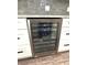 Modern wine fridge encased in white cabinets and topped with a tile backsplash at 1147 Halapa Way, Trinity, FL 34655