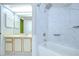 Bright bathroom featuring a tiled shower-tub combo, large mirrors, and white cabinetry at 12846 Tallowood Dr, Riverview, FL 33569