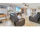 Spacious living room featuring wood-look tile floors, ceiling fan, a TV, and comfortable brown leather seating at 13263 86Th Ave, Seminole, FL 33776