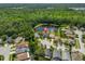 Aerial shot of a home with a dark roof next to a pond, surrounded by lush trees and neighborhood houses at 14502 Pond Cypress Way, Tampa, FL 33626