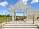 Inviting outdoor seating area under a pergola with comfortable chairs and landscaping under a clear sky at 17729 Nectar Flume Dr, Land O Lakes, FL 34638