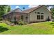 Spacious backyard featuring a screened lanai, lush green lawn, and partial view of the home's exterior at 1903 Curry Rd, Lutz, FL 33549
