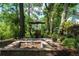 Relaxing backyard featuring a brick fire pit and outdoor dining area under a canopy of mature trees at 1903 Curry Rd, Lutz, FL 33549