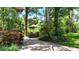 Secluded backyard features a brick patio with an outdoor dining area, shaded by mature trees and lush landscaping at 1903 Curry Rd, Lutz, FL 33549