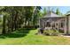View of screened lanai, surrounded by trees, showcasing outdoor living space and well-manicured lawn at 1903 Curry Rd, Lutz, FL 33549