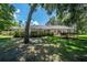 View of a sprawling backyard and the back exterior of the home, surrounded by lush greenery and mature trees at 1903 Curry Rd, Lutz, FL 33549
