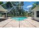 Beautiful in-ground pool surrounded by screened-in patio and lush greenery at 1903 Curry Rd, Lutz, FL 33549